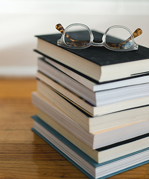 stack of 9 books with eyeglasses on top